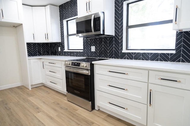 kitchen featuring tasteful backsplash, stainless steel appliances, light hardwood / wood-style floors, and white cabinets