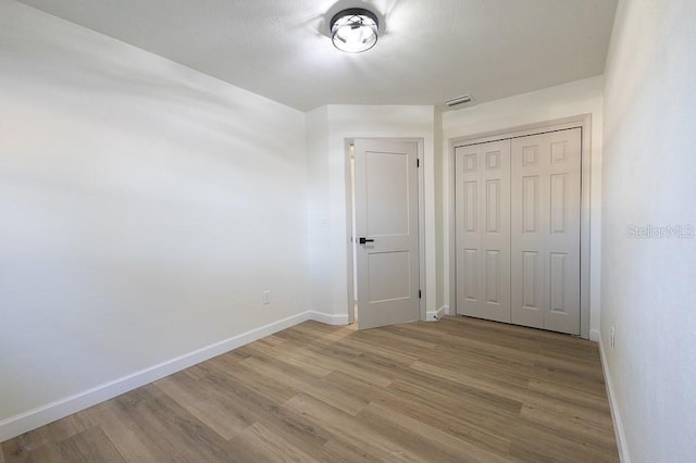 unfurnished bedroom with hardwood / wood-style flooring and a closet