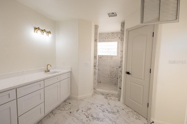 bathroom with a tile shower and vanity