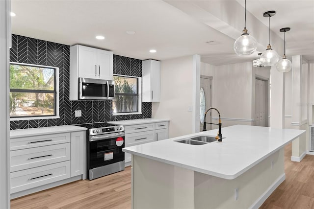 kitchen featuring sink, a center island with sink, appliances with stainless steel finishes, pendant lighting, and white cabinets