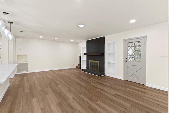 unfurnished living room with hardwood / wood-style flooring, a fireplace, and built in shelves