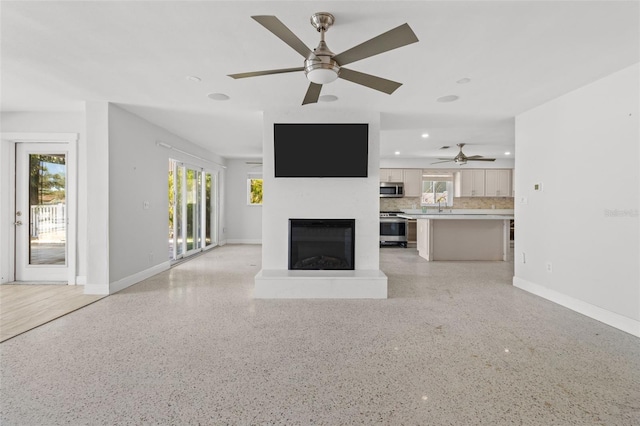 unfurnished living room featuring ceiling fan and sink