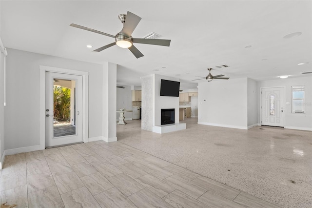 unfurnished living room featuring a large fireplace and ceiling fan