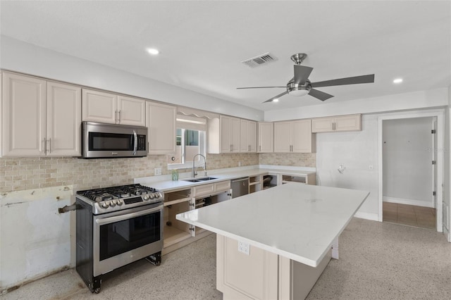 kitchen with a center island, backsplash, sink, ceiling fan, and appliances with stainless steel finishes