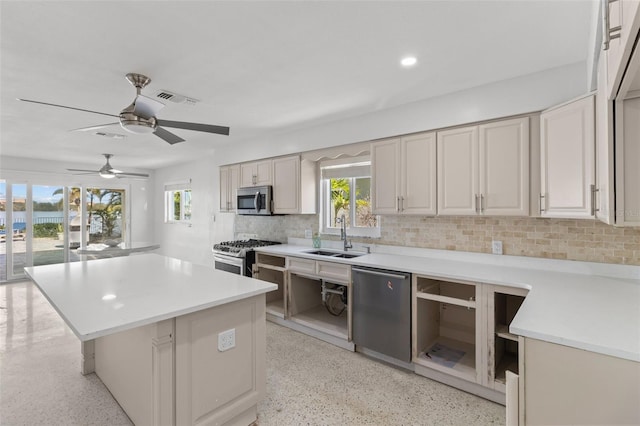 kitchen featuring a center island, backsplash, sink, ceiling fan, and appliances with stainless steel finishes