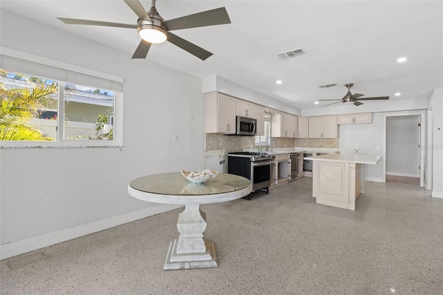 kitchen with a center island, sink, appliances with stainless steel finishes, tasteful backsplash, and white cabinetry