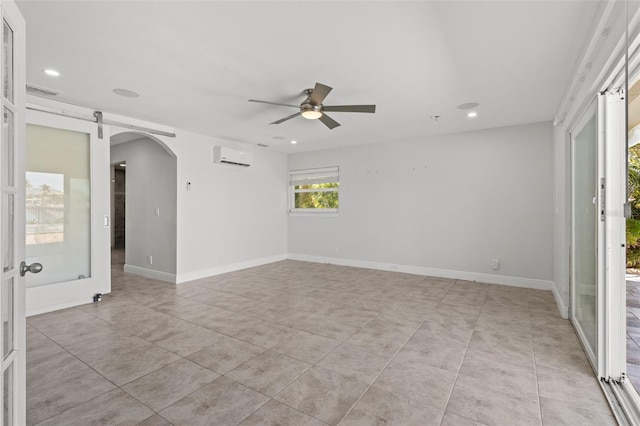 unfurnished room featuring ceiling fan, a barn door, and an AC wall unit