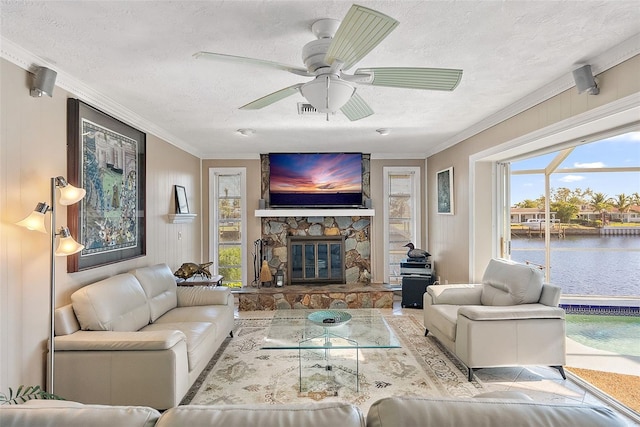 living room featuring plenty of natural light, a stone fireplace, a textured ceiling, and crown molding