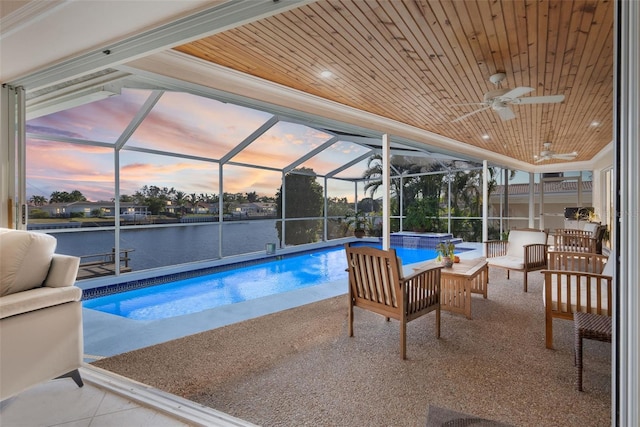 pool at dusk featuring a jacuzzi, an outdoor hangout area, a water view, and glass enclosure