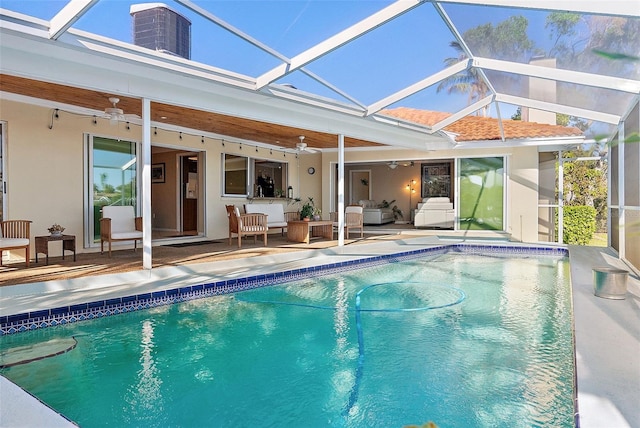 view of swimming pool with glass enclosure, ceiling fan, a patio, and an outdoor hangout area