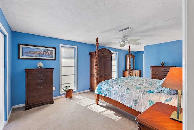 bedroom featuring a textured ceiling, light colored carpet, and ceiling fan