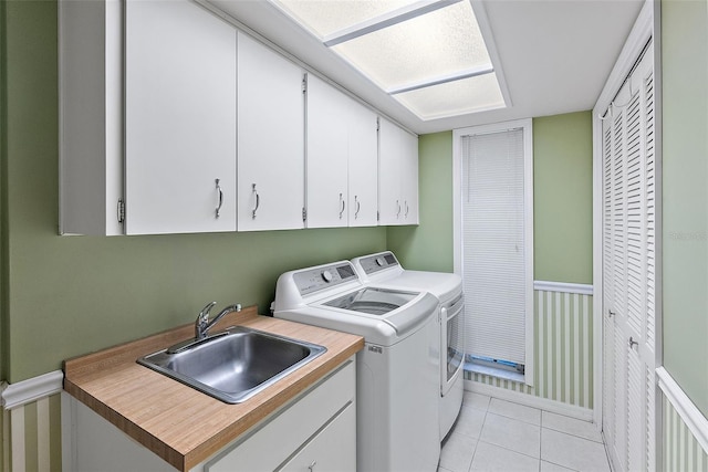 clothes washing area with sink, light tile patterned floors, cabinets, and independent washer and dryer