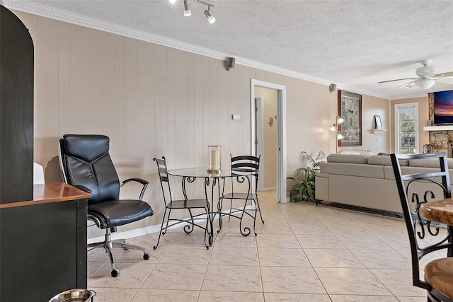 interior space featuring ceiling fan, a fireplace, a textured ceiling, and ornamental molding