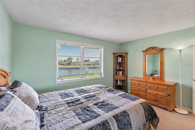 bedroom with carpet flooring, a water view, and a textured ceiling