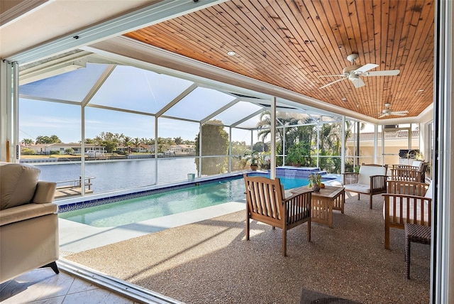 view of pool with glass enclosure, outdoor lounge area, a water view, and a patio