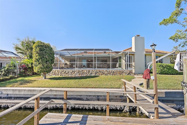 rear view of property with glass enclosure, a yard, and a water view