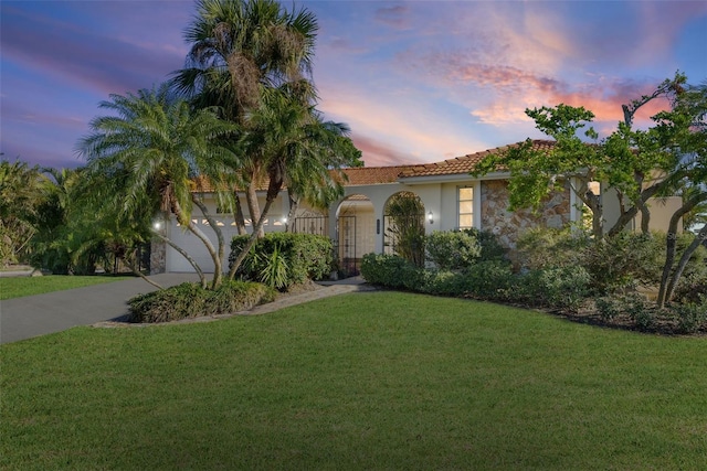 mediterranean / spanish-style home featuring a lawn and a garage