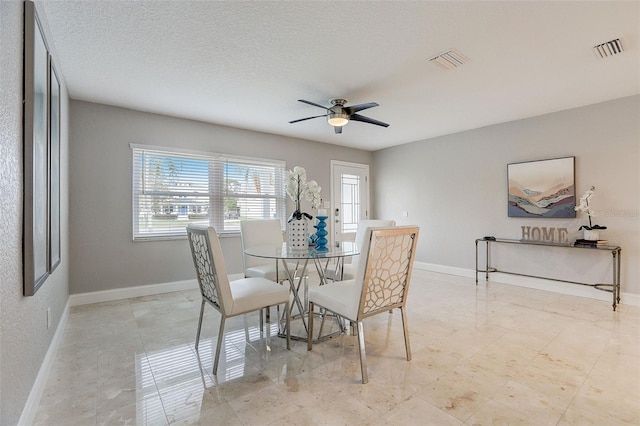 dining area featuring ceiling fan and a textured ceiling