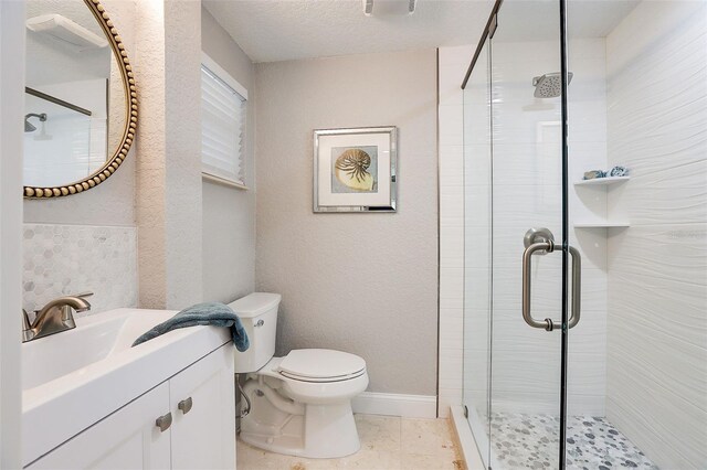 bathroom featuring tile patterned flooring, a textured ceiling, toilet, a shower with door, and vanity