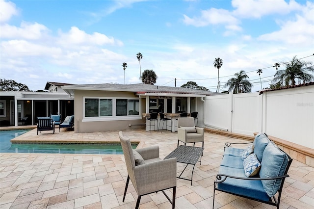 rear view of property featuring an outdoor living space, a fenced in pool, exterior bar, and a patio