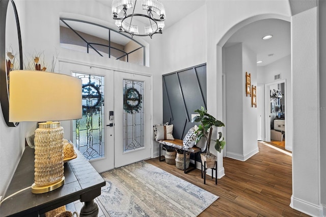 entryway featuring french doors, a towering ceiling, a chandelier, and dark hardwood / wood-style floors