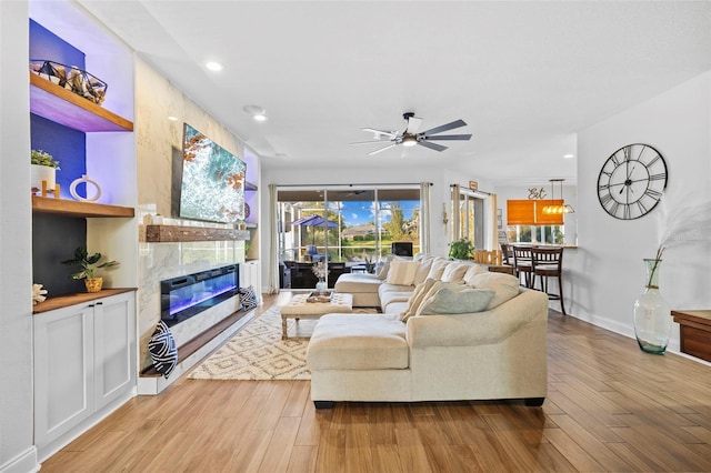 living room with ceiling fan, light hardwood / wood-style flooring, and a high end fireplace