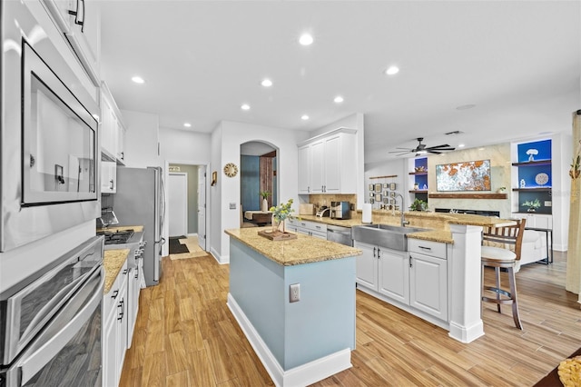 kitchen featuring a breakfast bar, stainless steel appliances, sink, a center island, and white cabinetry