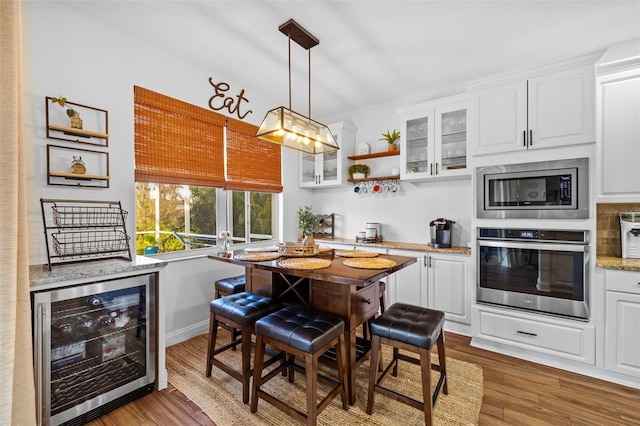 kitchen featuring light stone countertops, wine cooler, hardwood / wood-style floors, white cabinets, and appliances with stainless steel finishes