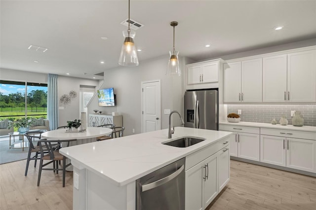 kitchen with white cabinets, appliances with stainless steel finishes, light wood-type flooring, and decorative light fixtures