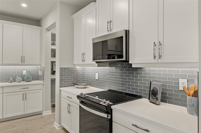 kitchen featuring tasteful backsplash, white cabinetry, stainless steel appliances, and light wood-type flooring