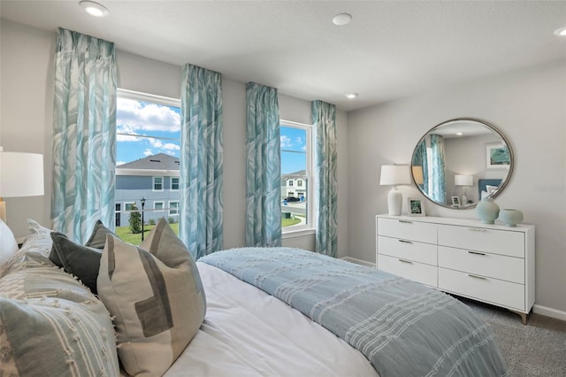 bedroom featuring dark colored carpet, a textured ceiling, and multiple windows