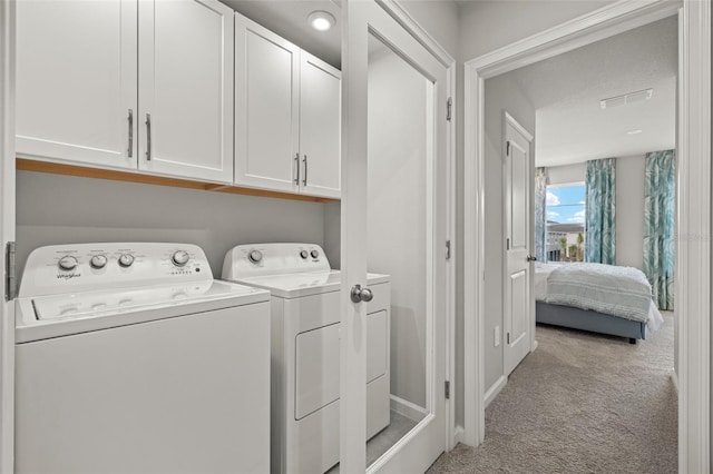 washroom with separate washer and dryer, light colored carpet, and cabinets