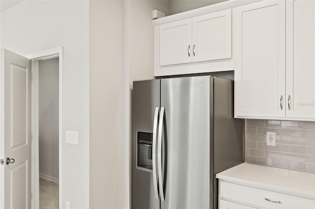 kitchen with white cabinetry, stainless steel fridge, and tasteful backsplash