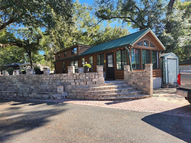 view of front of property featuring a patio and a shed