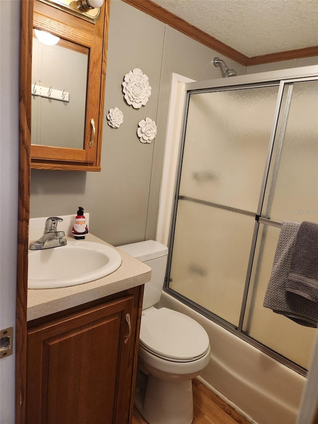 full bathroom featuring hardwood / wood-style floors, vanity, crown molding, bath / shower combo with glass door, and a textured ceiling