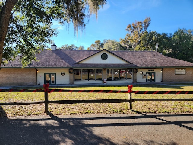 single story home with french doors and a front lawn