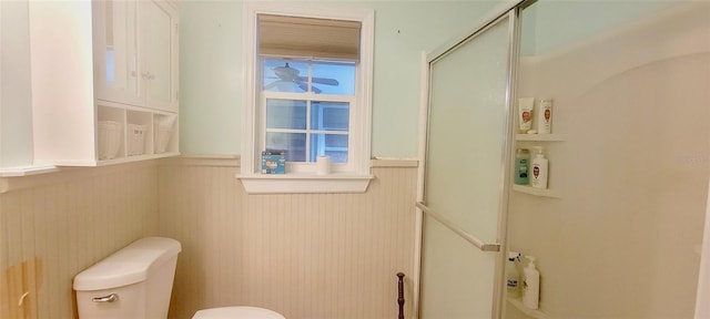 bathroom featuring a shower with door and toilet