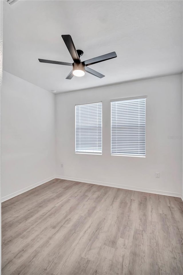 empty room with ceiling fan and light hardwood / wood-style flooring