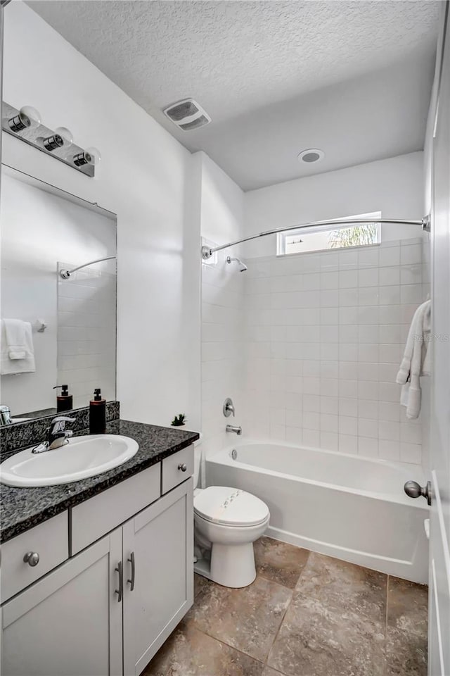 full bathroom featuring a textured ceiling, vanity, and tiled shower / bath combo