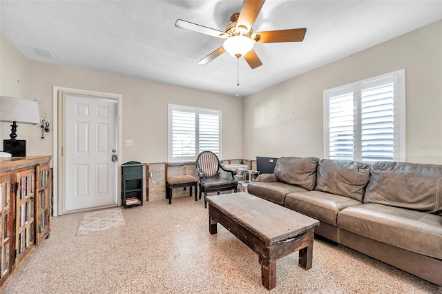 living room with a textured ceiling and ceiling fan