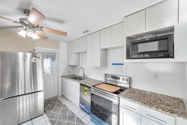 kitchen with appliances with stainless steel finishes, light stone counters, sink, light tile patterned floors, and white cabinetry