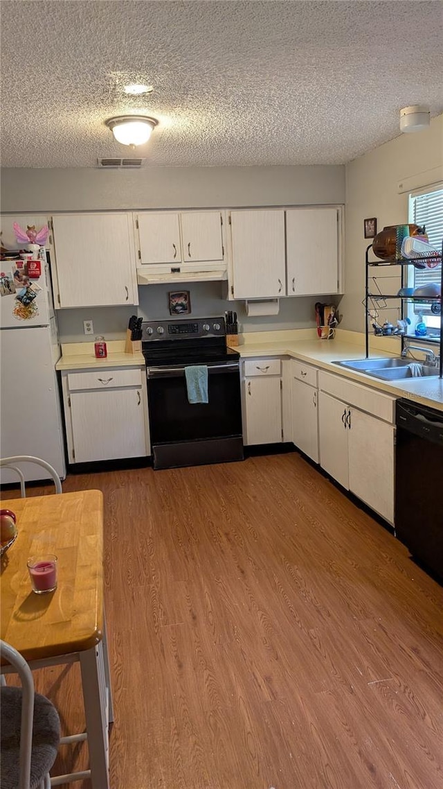 kitchen with black appliances, white cabinets, sink, and a textured ceiling