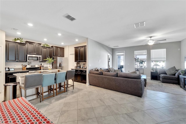 living room with light tile patterned floors, ceiling fan, and sink