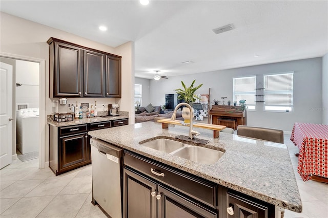 kitchen with ceiling fan, dishwasher, sink, an island with sink, and washer / dryer