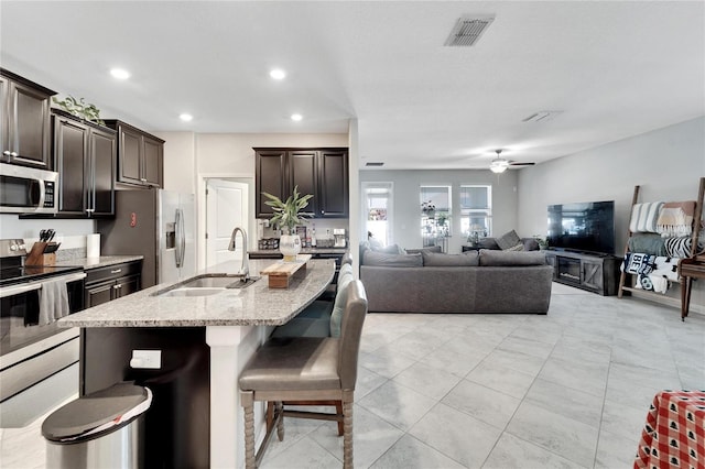 kitchen with a center island with sink, a kitchen breakfast bar, sink, ceiling fan, and appliances with stainless steel finishes