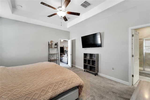 carpeted bedroom with a tray ceiling, ceiling fan, and ensuite bathroom