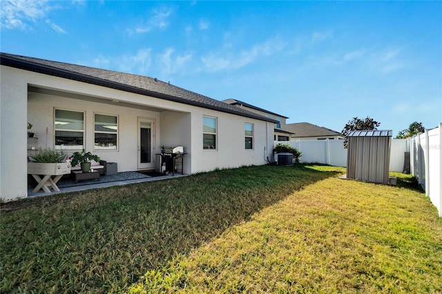 back of property featuring a lawn, a storage unit, and central air condition unit