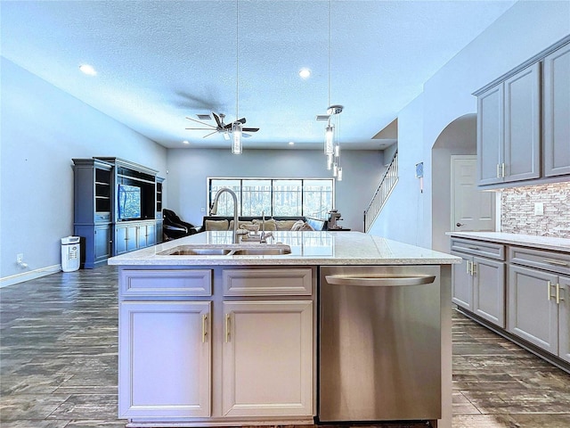 kitchen featuring gray cabinetry, dishwasher, a kitchen island with sink, sink, and a textured ceiling