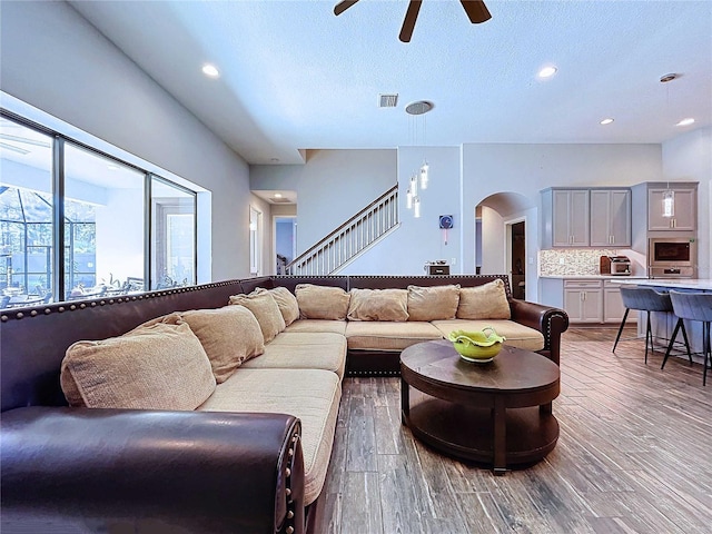 living room featuring ceiling fan, hardwood / wood-style floors, and a textured ceiling