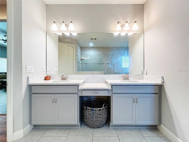 bathroom featuring tile patterned flooring, vanity, and a tile shower